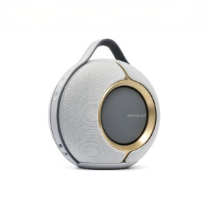 Portable round speaker with gold accents.