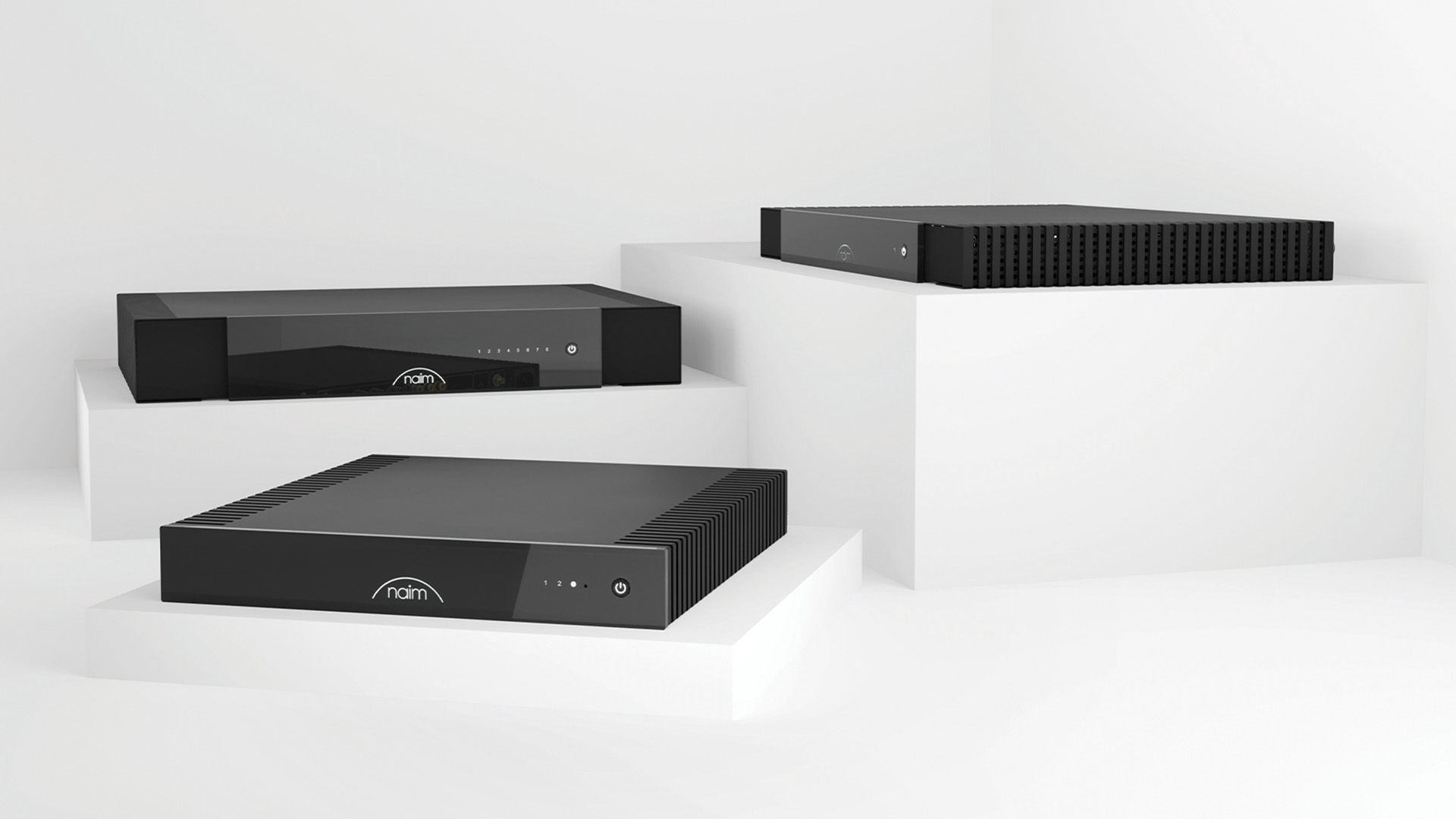 Black Naim audio equipment on white display stand