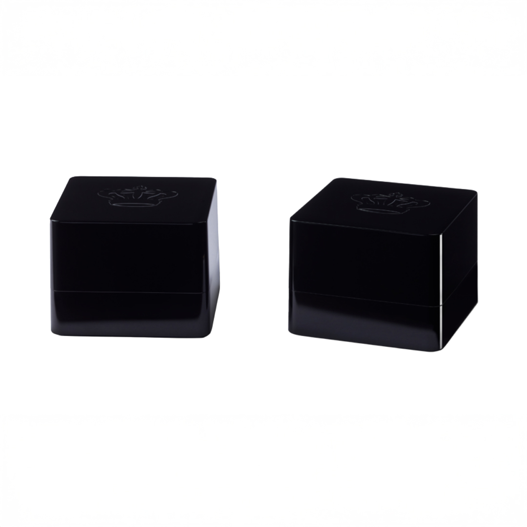 Two black cosmetic containers with embossed design.