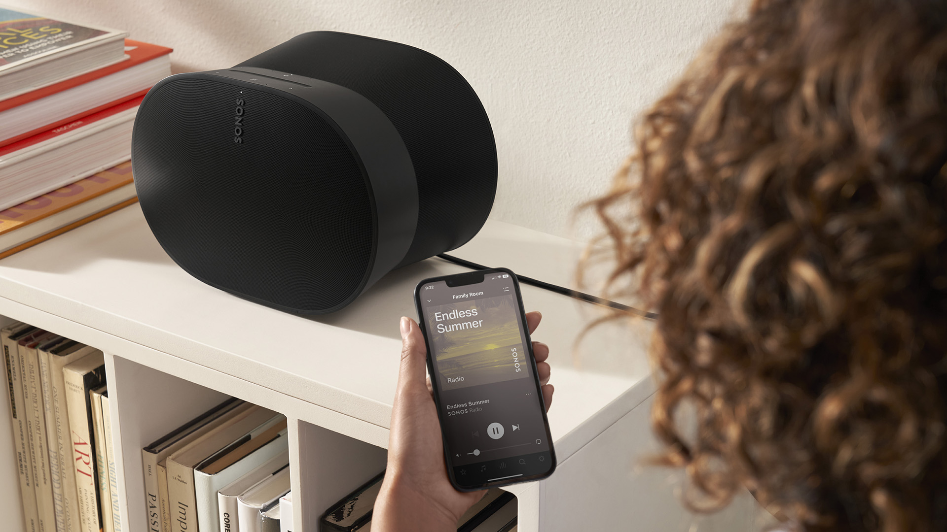 Person using smartphone to control a Sonos wireless speaker