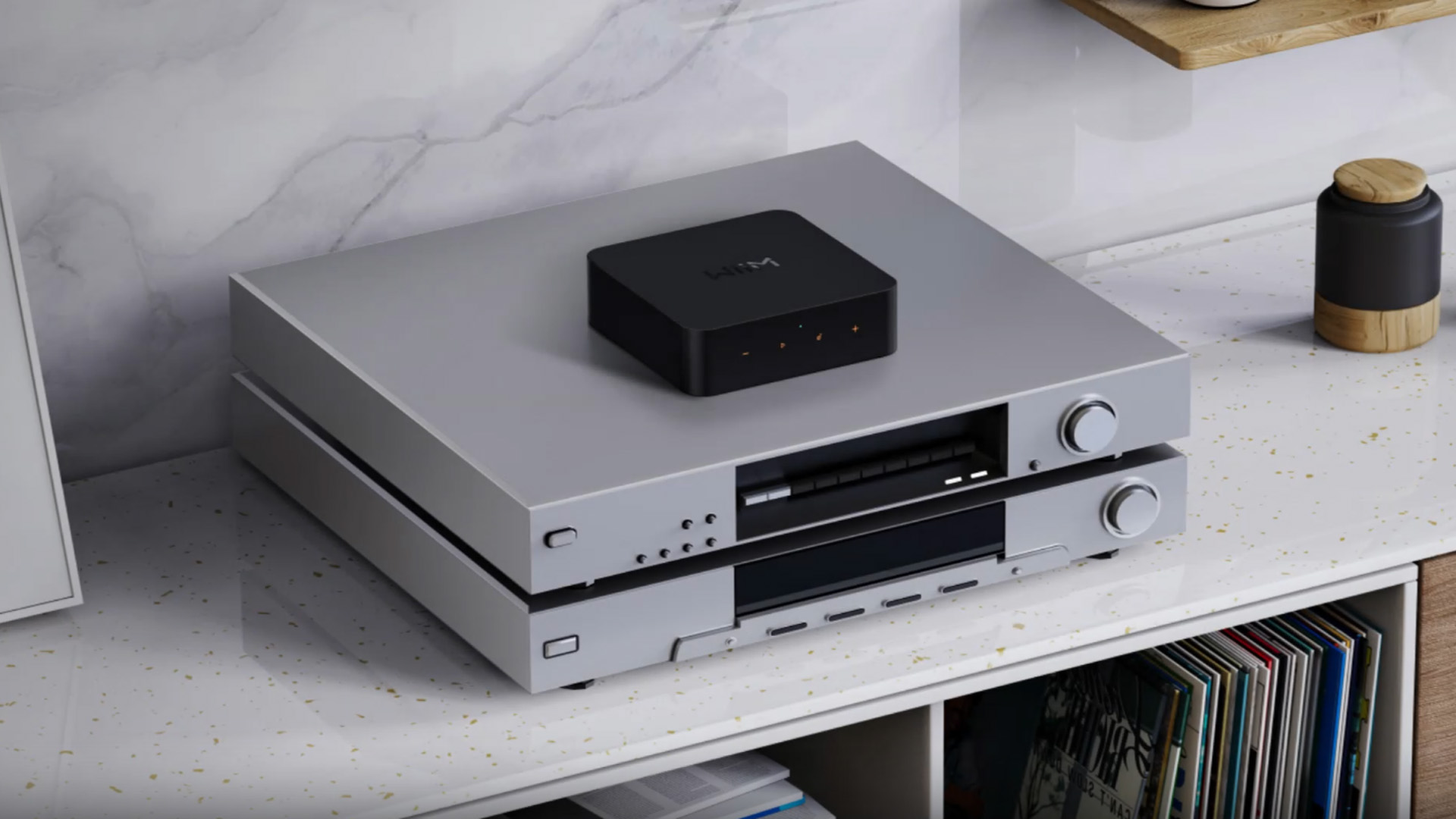 WiiM wireless audio streamer placed on top of audio equipment on white shelf